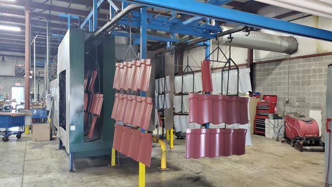 Metal roofing panels hanging from drying machine in plant