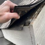 Close up of loose shingles being held up by a hand