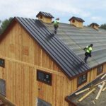 Cornett Roofing workers installing standing seam roof on steep barn