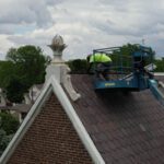 Cornett Roofing worker in bucket lift fixing slate roof on church