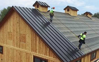 Cornett Roofing crew installing standing seam roof on wood barn